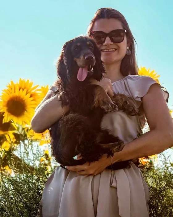 Sophie qui porte Alba, sa chienne, dans un champ de tournesols