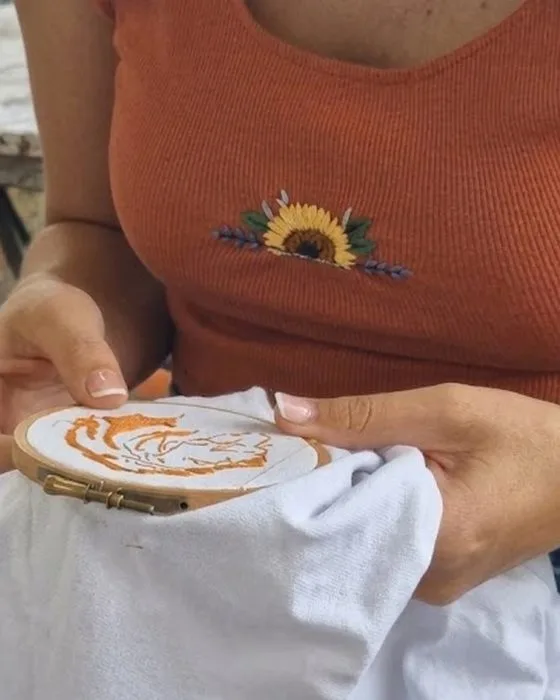 Sophie en train de broder un motif orange sur un tambour